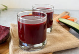 * hormone support juice with beets carrots and turmeric in a glass, beet and turmeric juice for natural hormone balance, anti-inflammatory beet carrot cucumber juice recipe, healing turmeric powder stirred into hormone support juice
