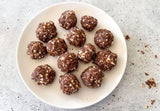 Happy Cacao bliss balls on white plate dusted with cacao, Hands rolling cacao energy balls, Ingredients for cacao bliss balls: dates, almonds, Happy Cacao, Cacao bliss balls close up showing texture