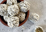 green lemon balls with daily greens on a white plate with lemon slices, no bake lemon energy balls with wheatgrass moringa spirulina powder, zesty green superfood snack balls rolled in lemon zest and coconut